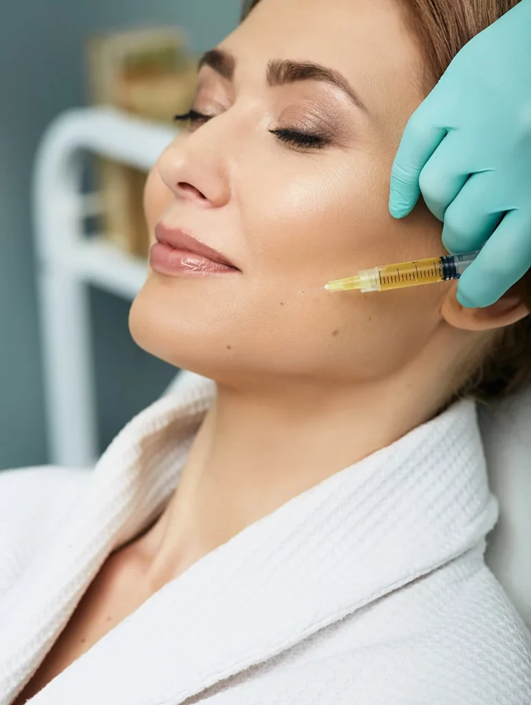 Patient receiving PRP (Platelet-Rich Plasma) injection on the cheek area by a professional wearing green gloves for skin rejuvenation.